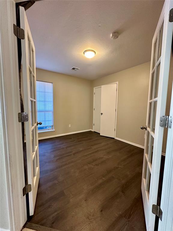 empty room with french doors and dark wood-type flooring