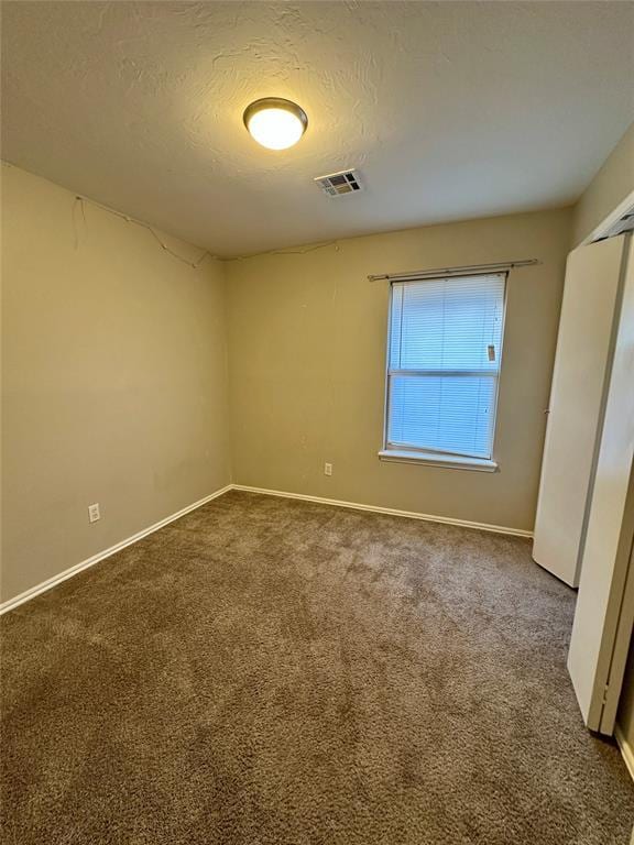 carpeted empty room with a textured ceiling