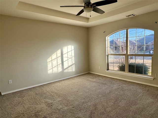 carpeted empty room featuring a mountain view, a tray ceiling, and ceiling fan