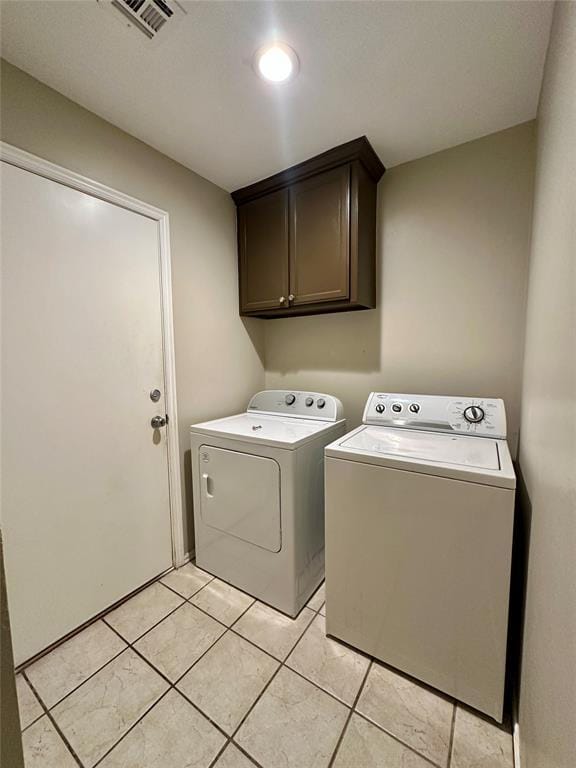 laundry area with washer and clothes dryer, cabinets, and light tile patterned floors