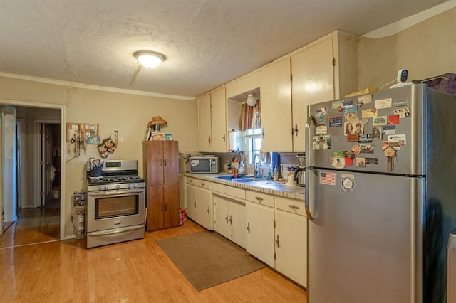 kitchen featuring white cabinetry, sink, appliances with stainless steel finishes, and light hardwood / wood-style flooring