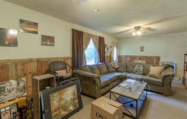 living room with a textured ceiling, carpet floors, ceiling fan, and wood walls