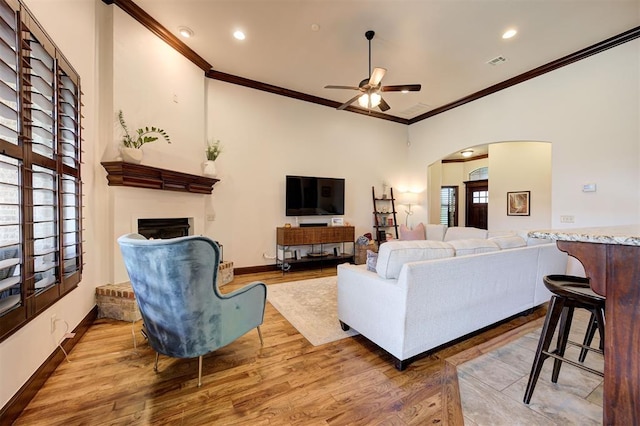 living room with ceiling fan, light wood-type flooring, and crown molding