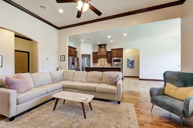 living room featuring ceiling fan, crown molding, and light hardwood / wood-style floors