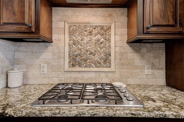 kitchen with stainless steel gas stovetop, light stone counters, decorative backsplash, and extractor fan