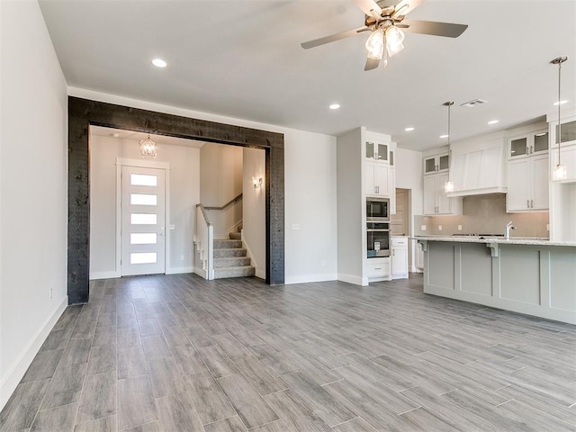 kitchen with built in microwave, premium range hood, oven, pendant lighting, and white cabinets