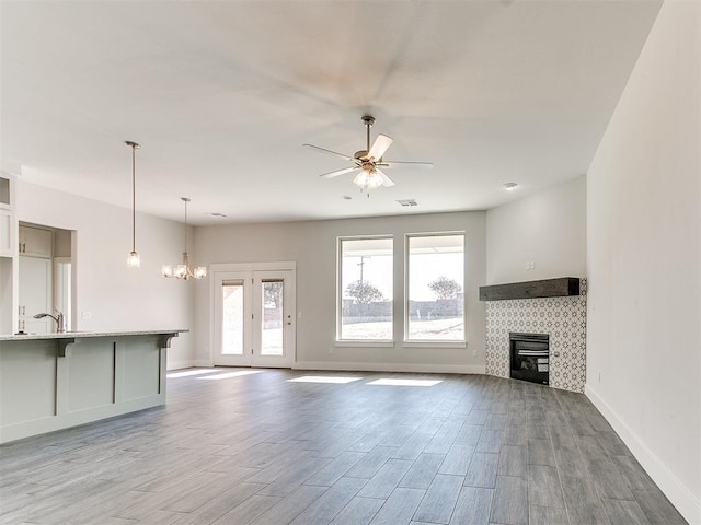 unfurnished living room featuring ceiling fan with notable chandelier, wood-type flooring, and sink