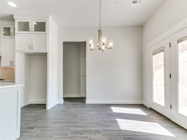 unfurnished dining area featuring plenty of natural light and an inviting chandelier