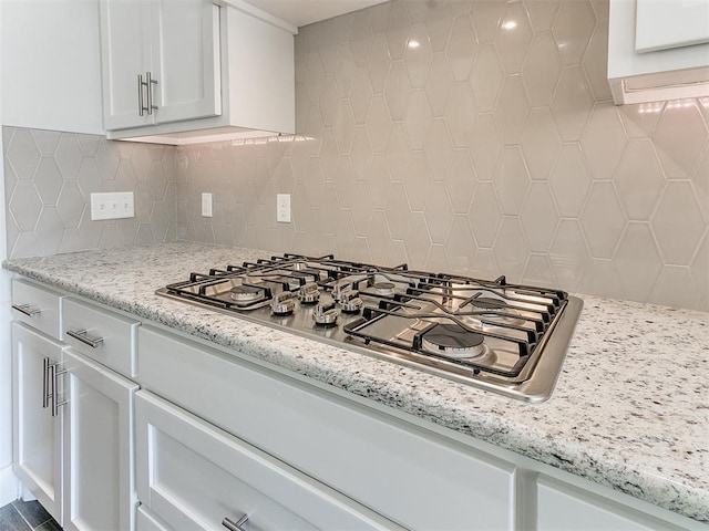 kitchen with white cabinetry, decorative backsplash, light stone countertops, and stainless steel gas cooktop