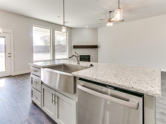 11400 NW 109th St, Yukon, OK 73099 - kitchen featuring stainless steel dishwasher, a ceiling fan, pendant lighting, a tiled fireplace, and light stone countertops