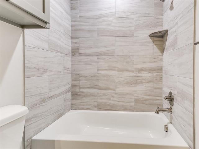 bathroom with tiled shower / bath combo and toilet