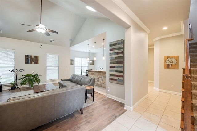 living room featuring ceiling fan, ornamental molding, lofted ceiling, and light wood-type flooring