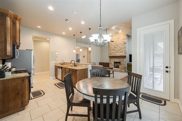 tiled dining room with a stone fireplace, sink, and a chandelier