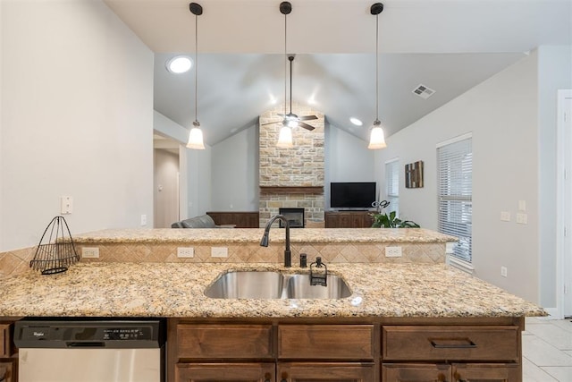 kitchen featuring a stone fireplace, sink, stainless steel dishwasher, and light stone counters