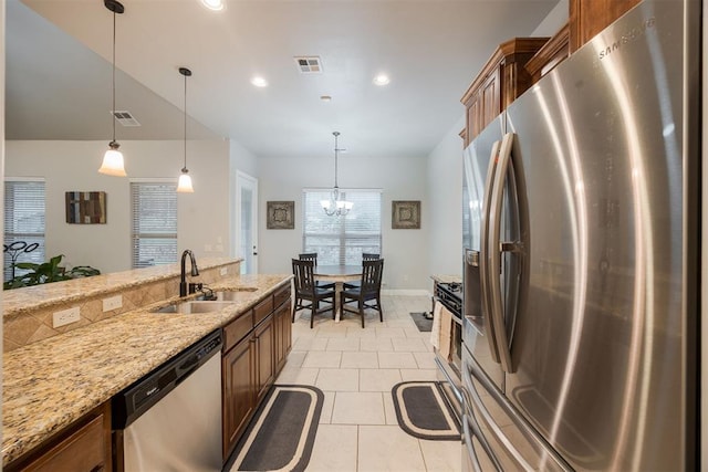 kitchen with pendant lighting, sink, light tile patterned floors, stainless steel appliances, and light stone countertops