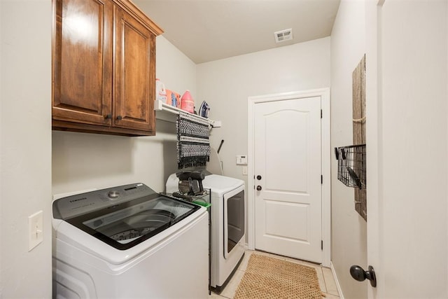 laundry area with separate washer and dryer, light tile patterned flooring, and cabinets