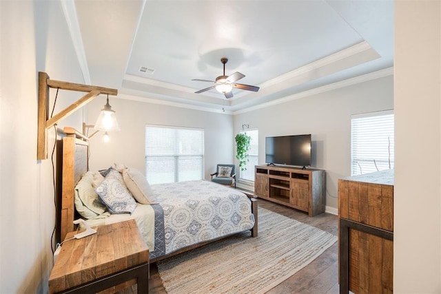 bedroom featuring hardwood / wood-style flooring, ceiling fan, crown molding, and a raised ceiling