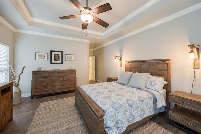 bedroom with ornamental molding, dark hardwood / wood-style floors, ceiling fan, and a tray ceiling