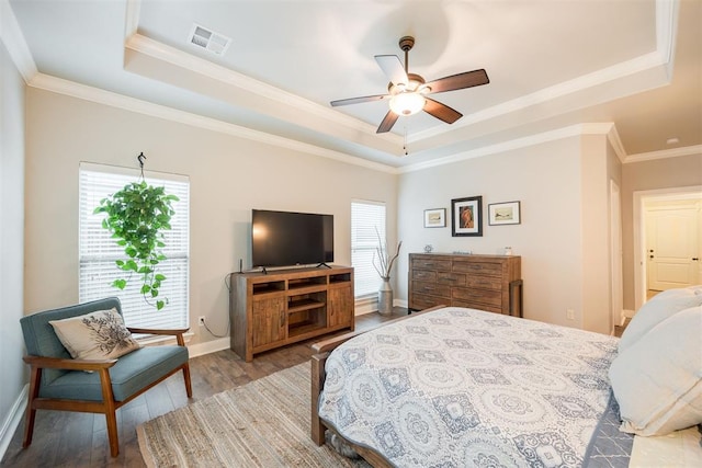 bedroom featuring wood-type flooring, ornamental molding, a raised ceiling, and ceiling fan