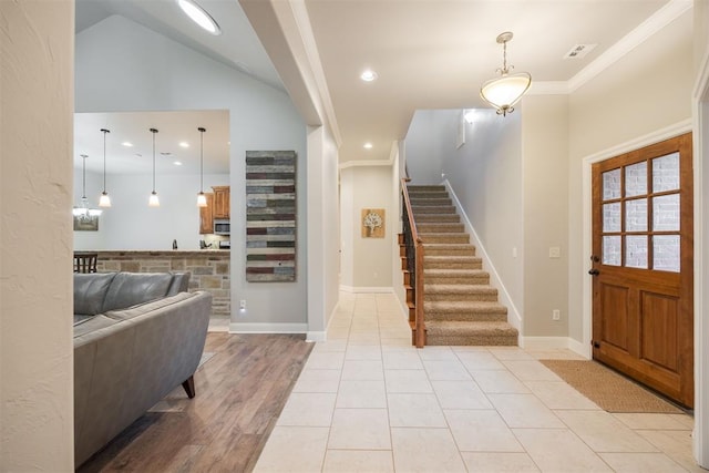 foyer with crown molding, vaulted ceiling, and light tile patterned floors