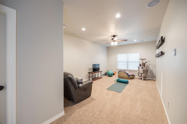 workout room with ceiling fan and light carpet