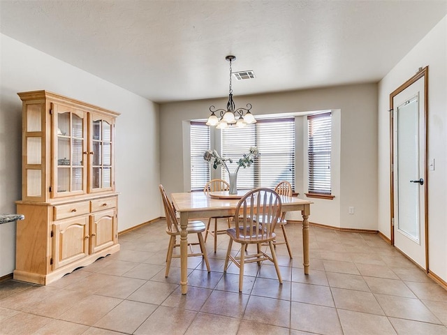 dining area featuring a healthy amount of sunlight, light tile patterned flooring, and an inviting chandelier