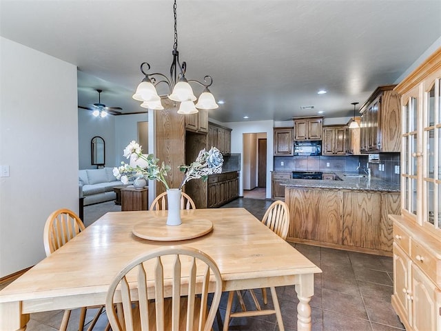 tiled dining room featuring ceiling fan with notable chandelier and sink