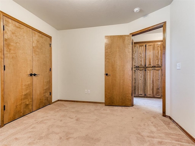 unfurnished bedroom with light colored carpet and a closet