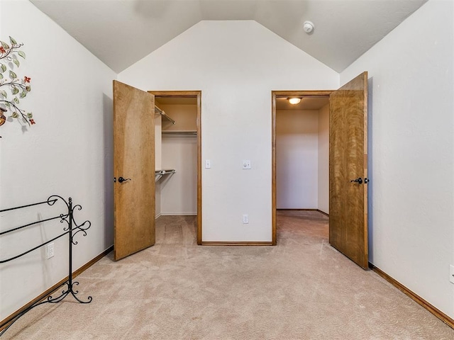 unfurnished bedroom with light colored carpet, a spacious closet, a closet, and lofted ceiling