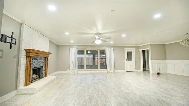 unfurnished living room featuring ceiling fan, ornamental molding, and a brick fireplace