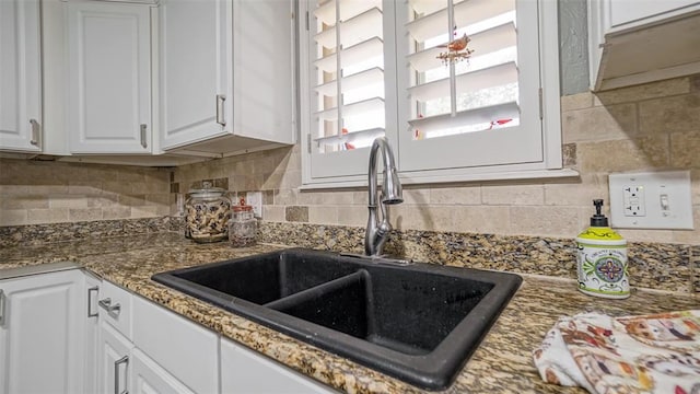 kitchen with tasteful backsplash, white cabinetry, sink, and stone countertops