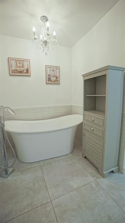 bathroom with a tub to relax in, tile patterned flooring, and an inviting chandelier