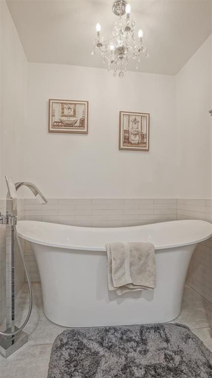 bathroom with an inviting chandelier, tile walls, and a bathing tub