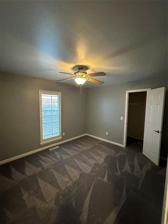 carpeted spare room featuring ceiling fan