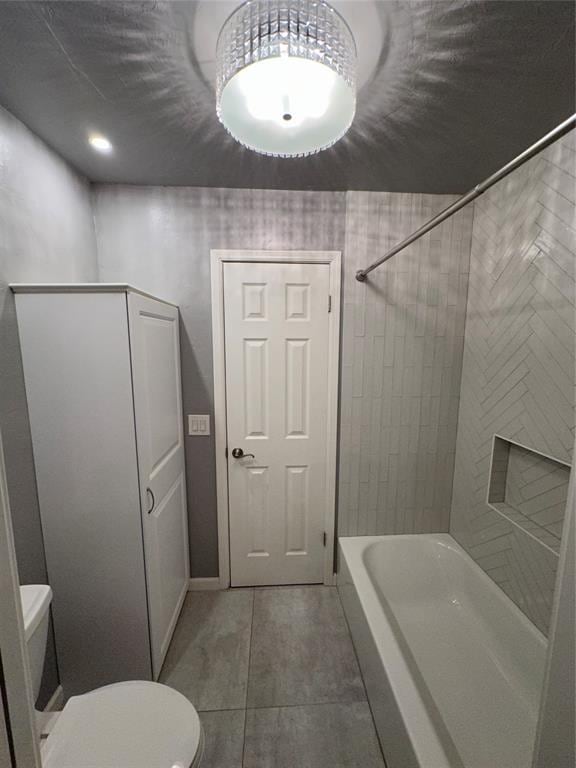 bathroom featuring tile patterned floors, tiled shower / bath, and toilet