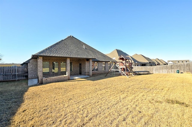 back of house featuring a yard and a playground