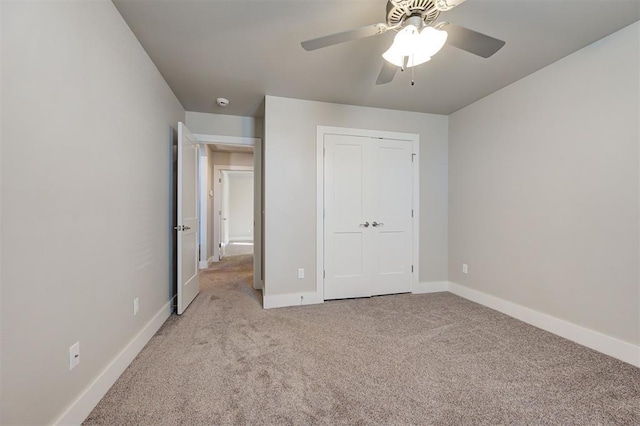 unfurnished bedroom featuring light colored carpet, a closet, and ceiling fan