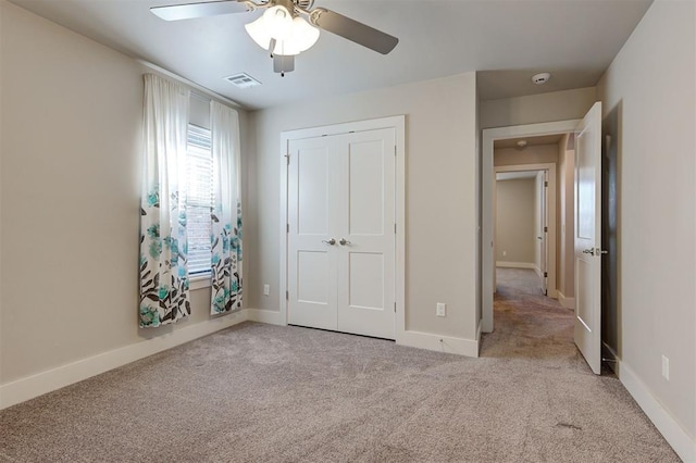 unfurnished bedroom featuring ceiling fan, light colored carpet, and a closet