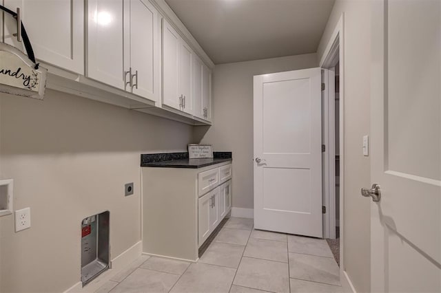 laundry room featuring electric dryer hookup, light tile patterned floors, and cabinets