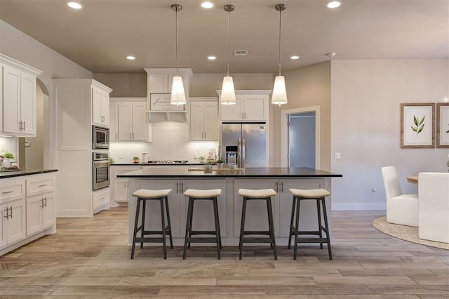 kitchen with decorative backsplash, hanging light fixtures, appliances with stainless steel finishes, a kitchen breakfast bar, and white cabinets