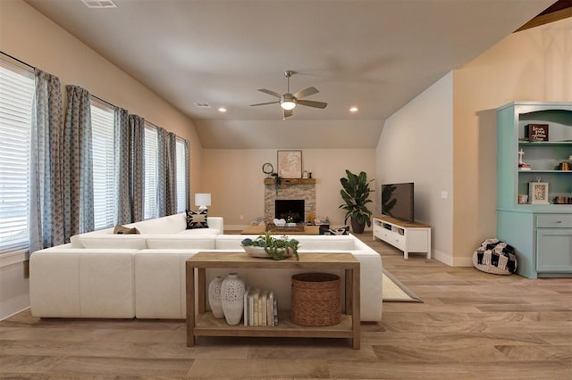 living room with ceiling fan, light wood-type flooring, lofted ceiling, and a fireplace