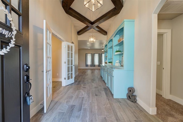 foyer entrance with french doors, coffered ceiling, a notable chandelier, beam ceiling, and light hardwood / wood-style flooring