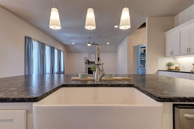 kitchen with a center island with sink, white cabinetry, sink, and pendant lighting