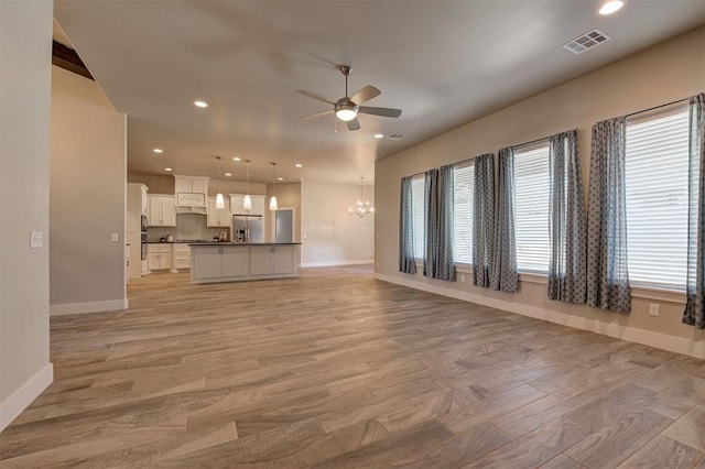 unfurnished living room with light hardwood / wood-style floors and ceiling fan with notable chandelier