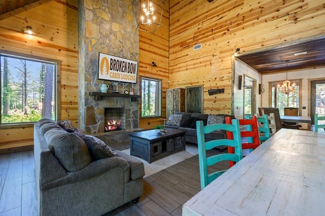 living room with wooden walls, a fireplace, a high ceiling, and a notable chandelier