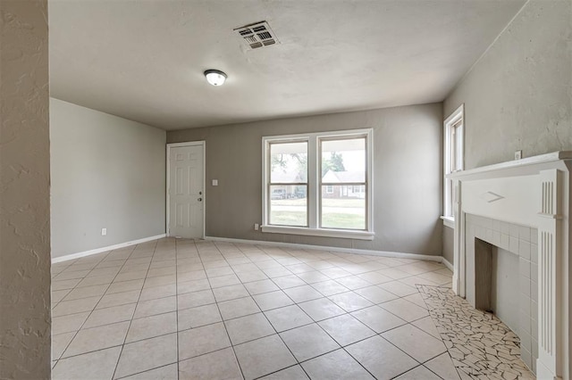 unfurnished living room with a tiled fireplace and light tile patterned floors