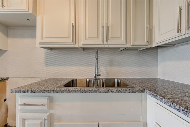 kitchen with sink, dark stone counters, and tasteful backsplash