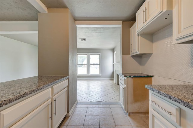 kitchen with light tile patterned floors and dark stone counters