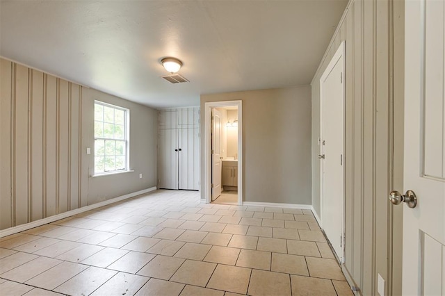 unfurnished bedroom with ensuite bathroom and light tile patterned floors