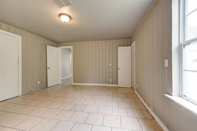 spare room featuring wood walls and light tile patterned floors